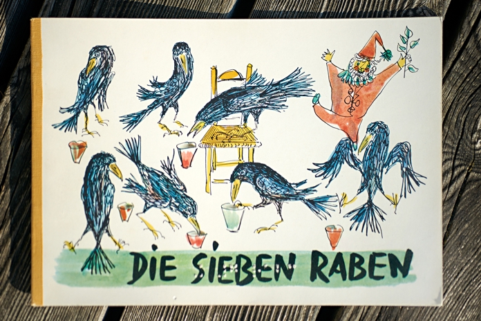 Buchcover «Die sieben Raben» Auf dem Buchcover sieht man den Zwerg und die sieben Raben, wie sie aus ihren Becherchen trinken.