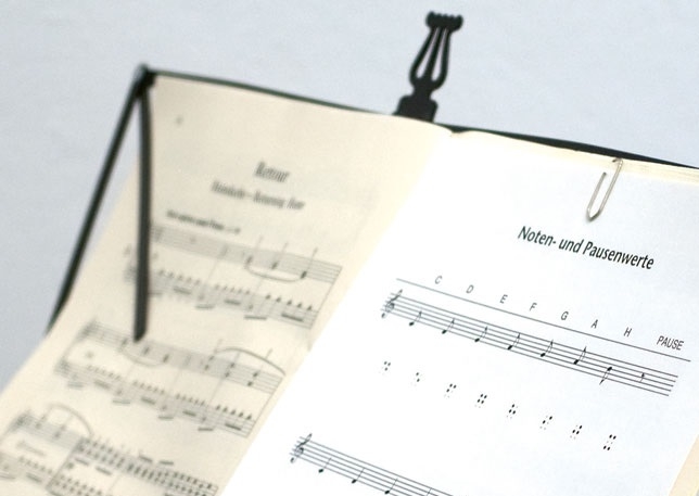 Notenständer mit Noten Nahaufnahme eines Notenständers, auf dem Notenblätter in Braille aufgeschlagen sind.